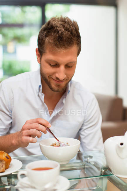 Улыбающийся человек завтракает за столом — стоковое фото