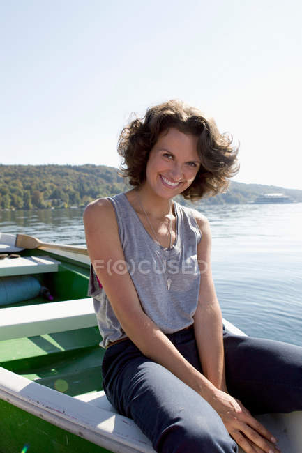 Mujer colgando pies de barco en el lago - foto de stock