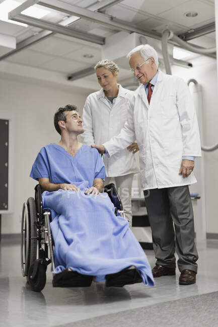 Врачи разговаривают с пациентом в инвалидном кресле — стоковое фото