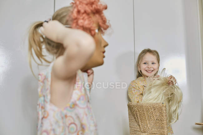 Meninas brincando com máscara facial e peruca no quarto — Fotografia de Stock