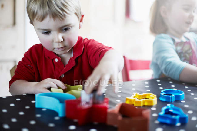 Kinder spielen mit Formen auf Tisch — Stockfoto