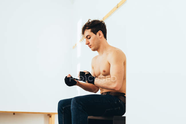 Mann sitzt in Umkleidekabine und wickelt Hände — Stockfoto