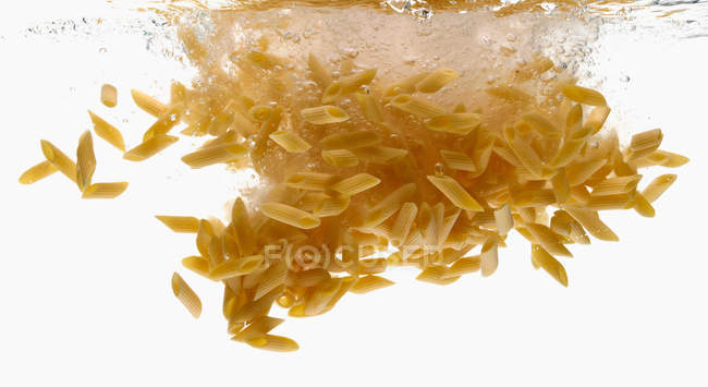 Gros plan sur les éclaboussures de pâtes dans l'eau — Photo de stock
