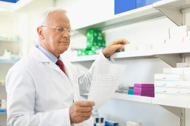 Pharmacist filling prescription, focus on foreground — Stock Photo