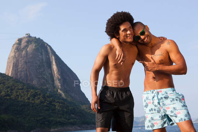 Two friends on beach with arms around each other, Rio de Janeiro, Brazil — Stock Photo