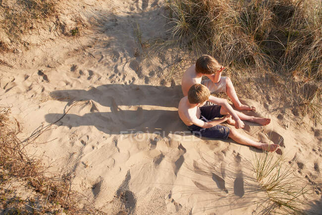 Due ragazzi seduti sulla spiaggia, angolo alto — Foto stock