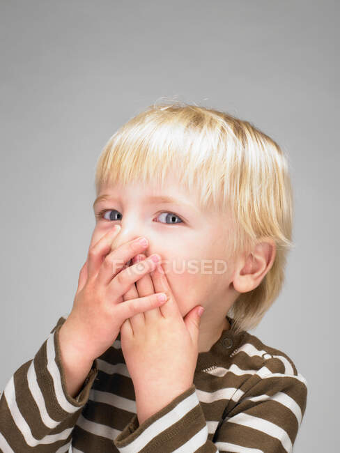 Kleiner Junge bedeckt seinen Mund — Stockfoto