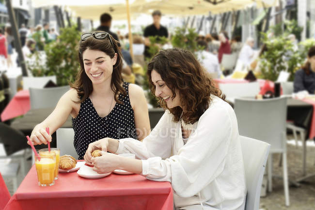 Two women chatting and having breakfast at sidewalk cafe, Milan, Italy — Stock Photo