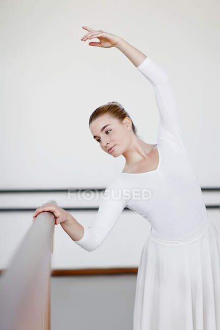 Ballet dancer posing at barre — Stock Photo