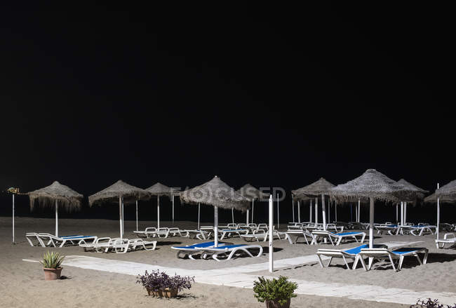 Empty lounge chairs on beach at nighttime — Stock Photo