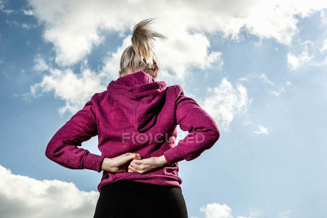 Jovem mulher se alongando com as mãos atrás das costas — Fotografia de Stock