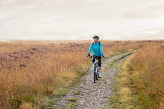 Woman mountain biking on dirt path — Stock Photo