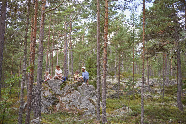 Familie sitzt auf Felsen im Wald und picknickt — Stockfoto