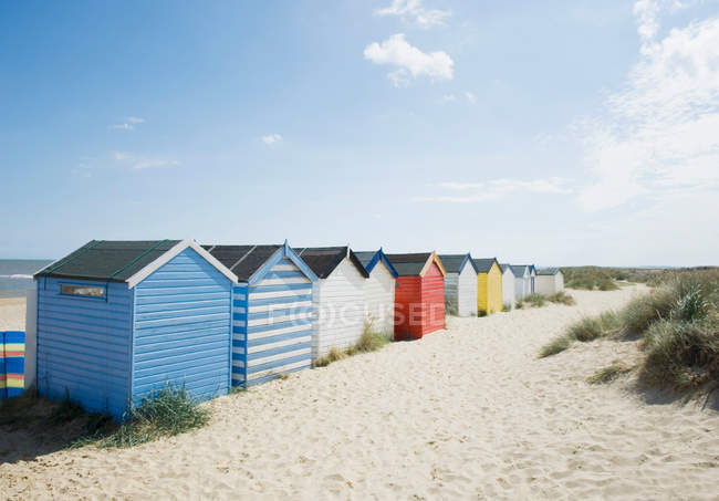 Яскраві кольорові хатини на пляжі під блакитним небом — стокове фото