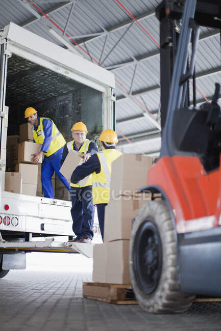 Workers unloading boxes from truck — Stock Photo