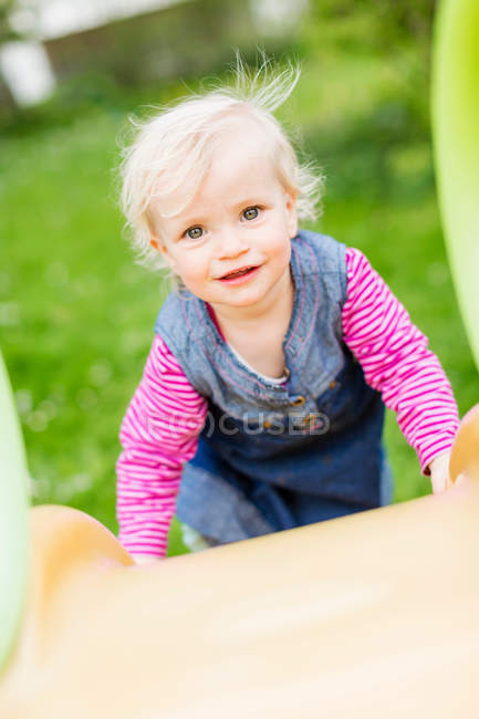 Toddler girl climbing slide in backyard — Stock Photo