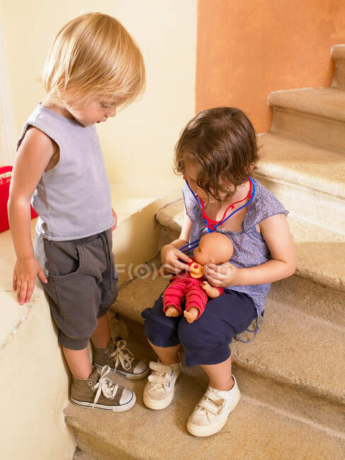Маленькі дівчата грають у лікаря з лялькою — стокове фото