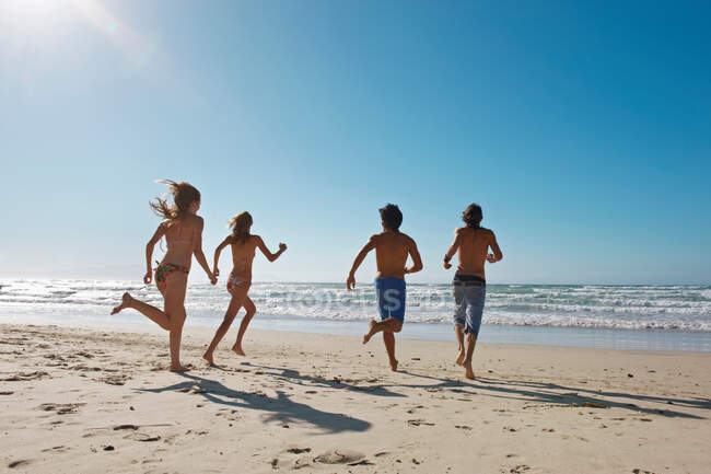 Young people running towards sea — Stock Photo