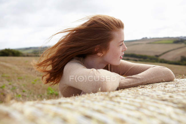 Девочка-подросток отдыхает на тюке сена, фокусируется на переднем плане — стоковое фото
