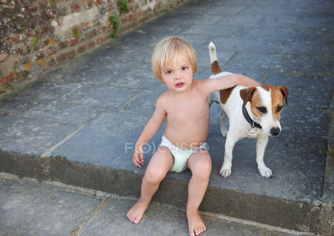 Baby boy playing with a dog — Stock Photo