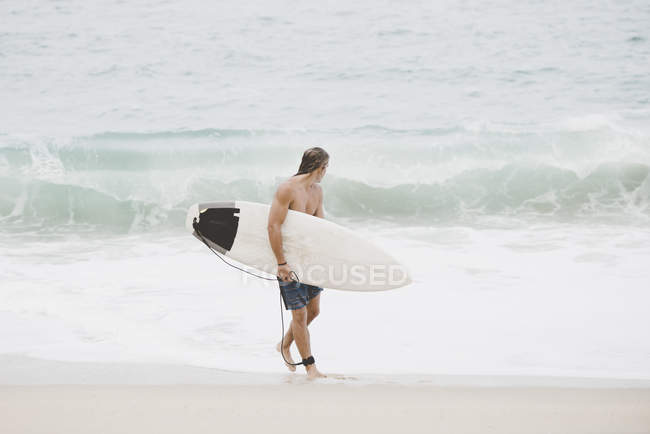 Surfista australiano con tabla de surf en la playa - foto de stock