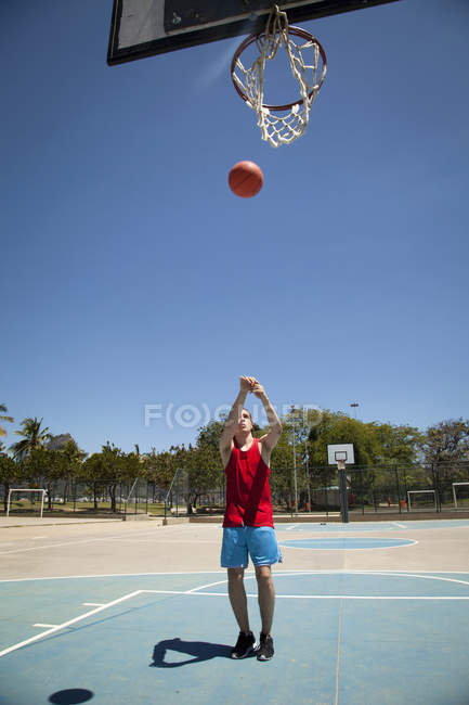 Jovem jogador de basquete masculino jogando bola em direção basquete aro — Fotografia de Stock