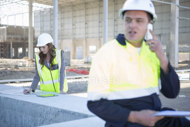 Gerenciador de site conversando no smartphone no local de construção — Fotografia de Stock