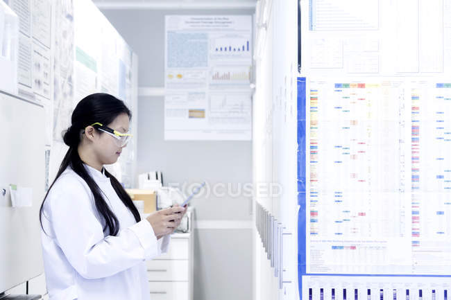 Cientista feminina olhando para tablet digital em laboratório — Fotografia de Stock