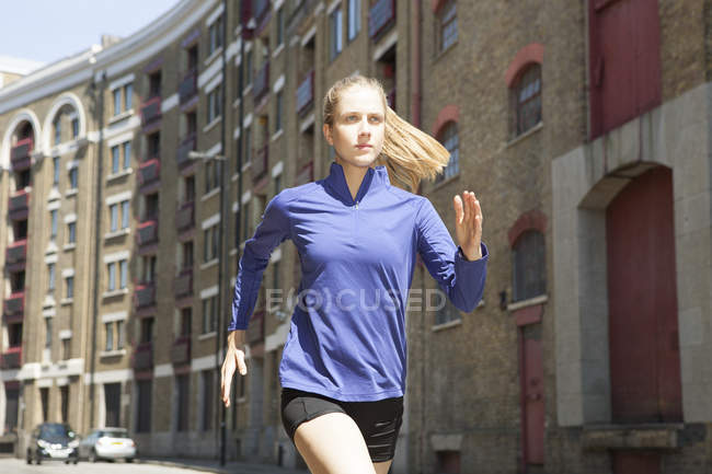 Runner jogging past building block, Wapping, Londra — Foto stock