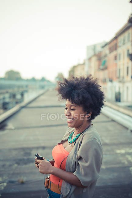 Young woman choosing music from smartphone in city — Stock Photo