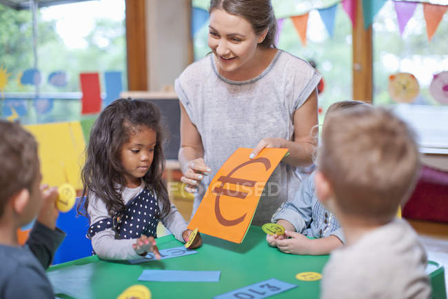 Teacher and pupils counting euro currency at nursery school — Stock Photo