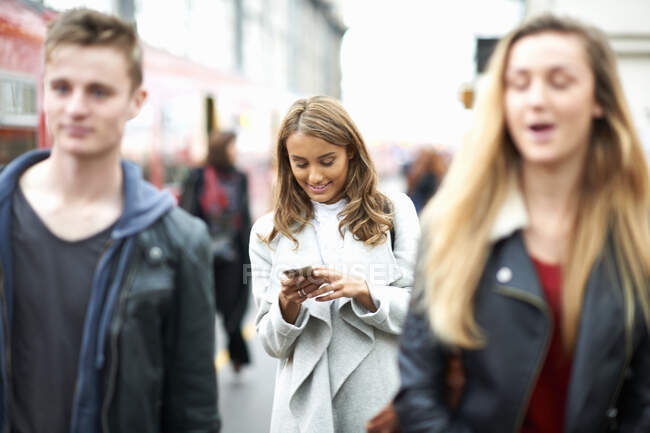 Молода жінка виходить на вулицю, використовуючи смартфон — стокове фото