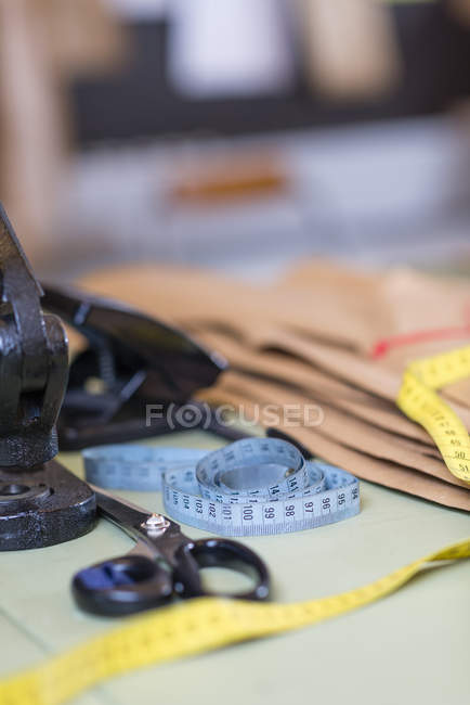Tijeras de modistos y cinta métrica en mesa de trabajo en taller - foto de stock