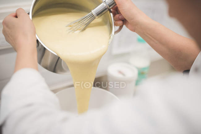 Abgeschnittenes Bild eines Bäckers, der in der Küche Mischung in Schüssel gießt — Stockfoto