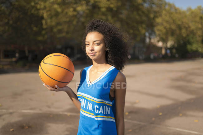 Portrait young female basketball player holding up basketball — Stock Photo