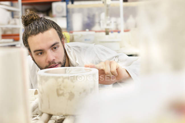 Мужчина гончар, работающий на цилиндрической форме в керамической мастерской — стоковое фото