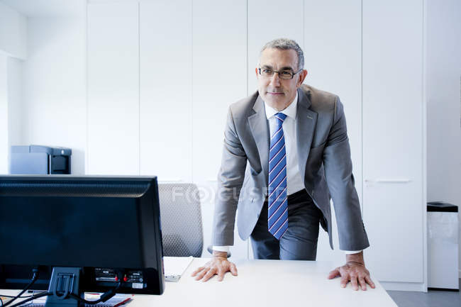 Reifer Geschäftsmann lehnt am Schreibtisch — Stockfoto