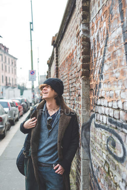 Musician walking along city wall, Milan, Italy — Stock Photo