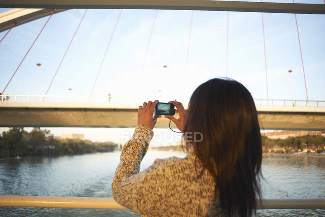 Maduro mulher turista fotografando no rio Guadalqivir em câmera digital, Sevilha, Espanha — Fotografia de Stock