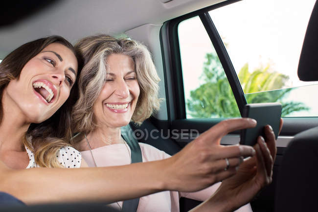Mujer mayor y su hija tomando selfie smartphone en el coche - foto de stock