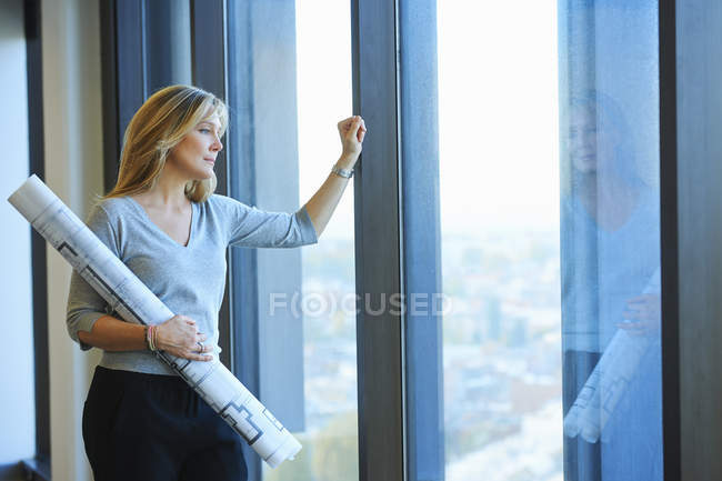 Retrato de arquitecta madura con planos en oficina de rascacielos, Bruselas, Bélgica - foto de stock
