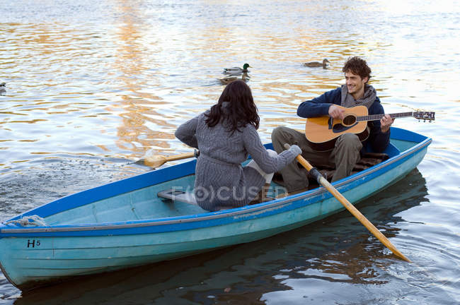 Homem tocando guitarra em barco de fileira — Fotografia de Stock