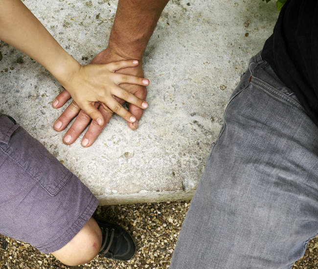 Overhead view of boys hand on top of fathers hand — Stock Photo