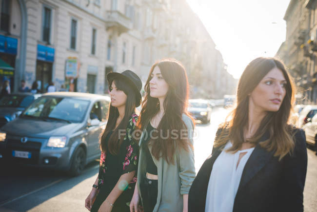 Trois jeunes femmes se promènent dans la rue de la ville — Photo de stock