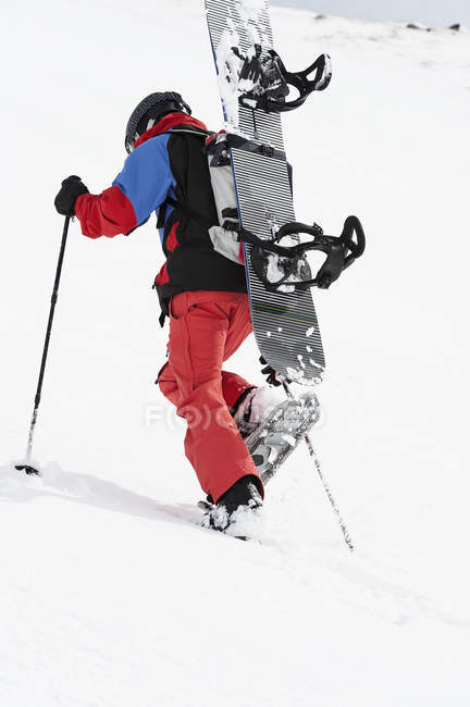 Snowboarder adulto medio caminando cuesta arriba, Obergurgl, Austria - foto de stock