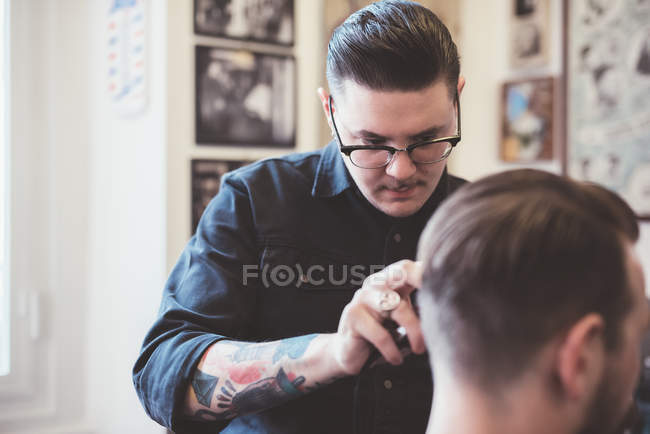 Barbeiro usando cortadores no cabelo do cliente na barbearia — Fotografia de Stock