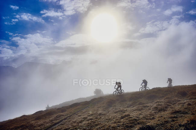 Tres personas en bicicleta de montaña, Valais, Suiza - foto de stock