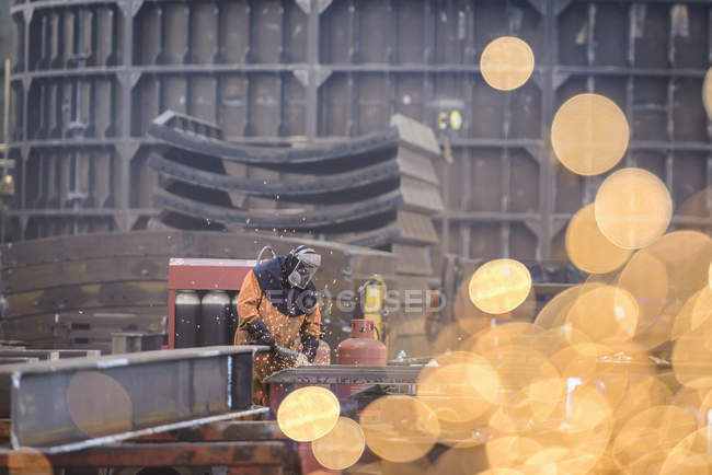 Worker grinding metal construction in marine fabrication factory — Stock Photo
