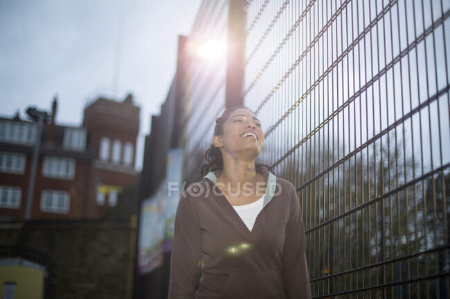 Молода жінка біля паркану, посміхаючись — стокове фото