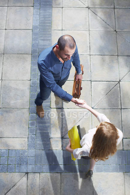 Businessman and business woman shaking hands, overhead view — Stock Photo
